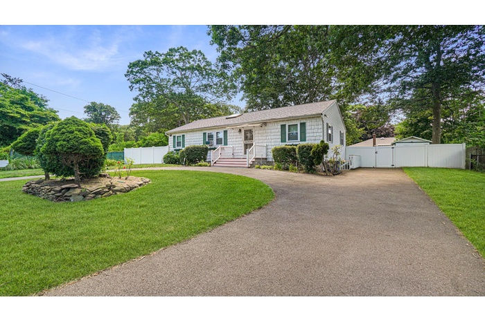 View of front of property with a gate, driveway, and a shingled roof