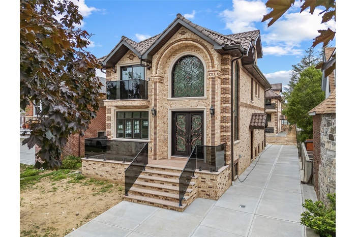 Tudor home featuring french doors, brick siding, and a balcony