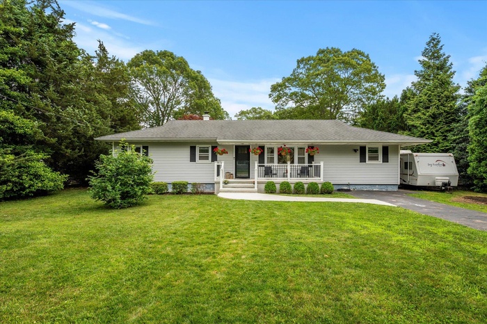 Single story home with covered porch, a front lawn, driveway, a chimney, and a shingled roof
