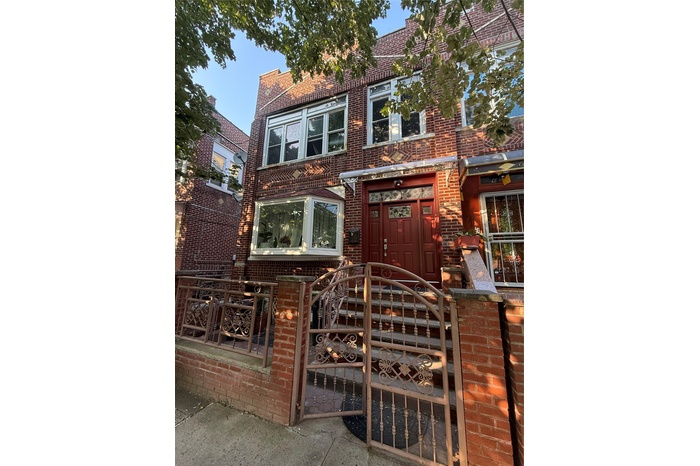 View of property featuring brick siding, a fenced front yard, and a gate