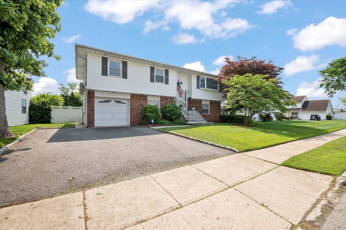 Split foyer home with brick siding, asphalt driveway, and an attached garage