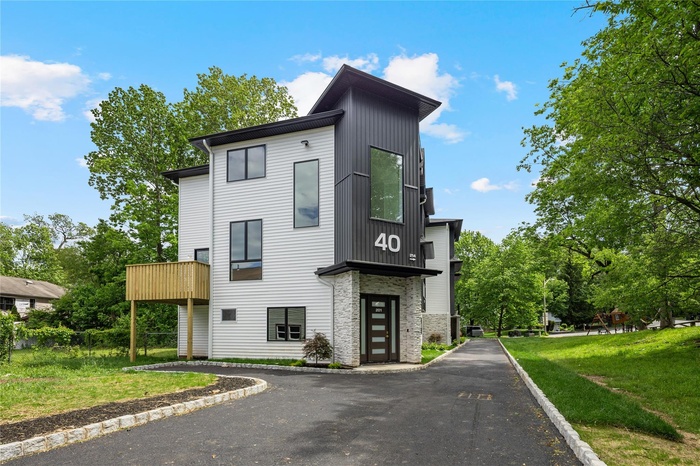 Modern home featuring stone siding and a front lawn