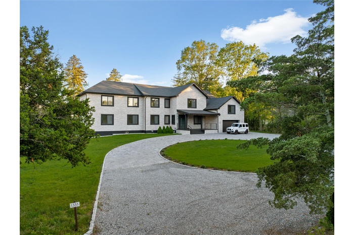 View of front facade featuring a front yard, curved driveway, and stone siding