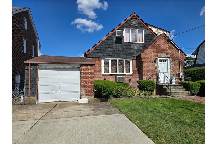View of front of home featuring driveway, a front yard, brick siding, and an attached garage