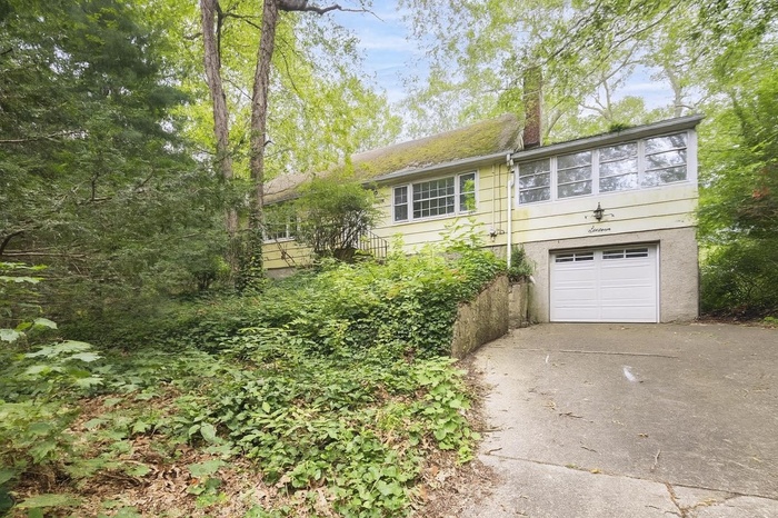 View of front of home with driveway, a garage, and a chimney