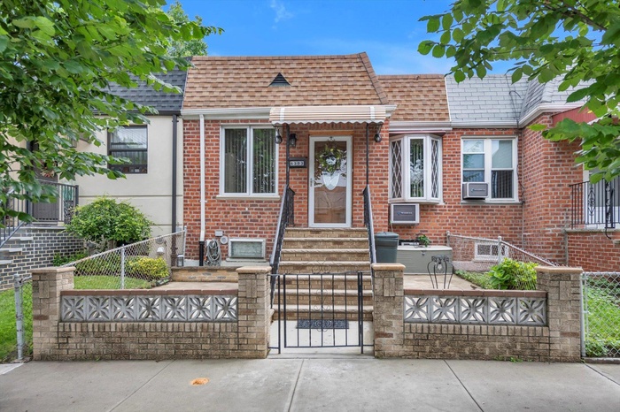 View of front facade featuring a fenced front yard, a shingled roof, and brick siding
