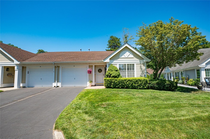 Single story home with a garage, asphalt driveway, a front lawn, and roof with shingles
