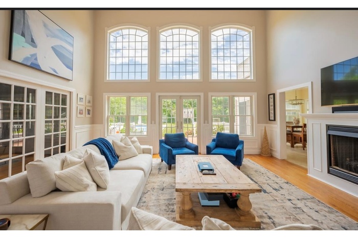 Living area with a towering ceiling, a decorative wall, a wainscoted wall, a fireplace, and wood finished floors