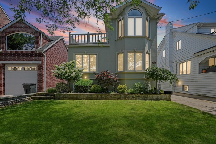 View of front facade featuring a balcony, stucco siding, a yard, and brick siding