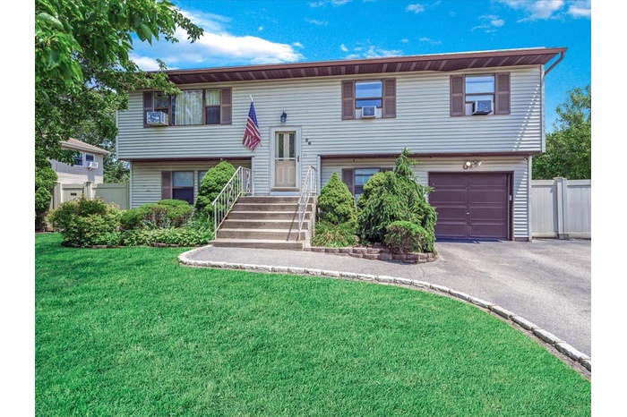 Bi-level home with an attached garage, asphalt driveway, and cooling unit