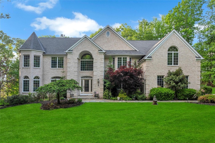 View of front of property with a front lawn, roof with shingles, and brick siding