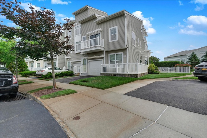 View of property with a balcony, a garage, and driveway