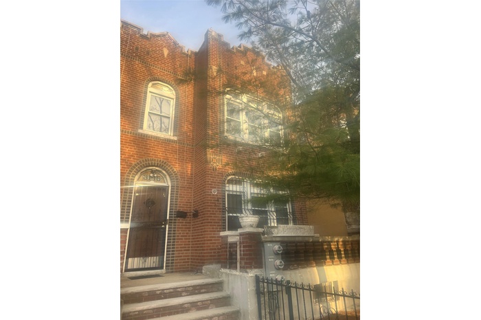 View of front facade featuring brick siding and a fenced front yard