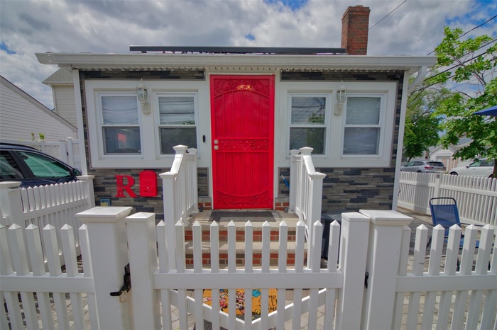 Doorway to property with fence, a chimney, stone siding, and a gate