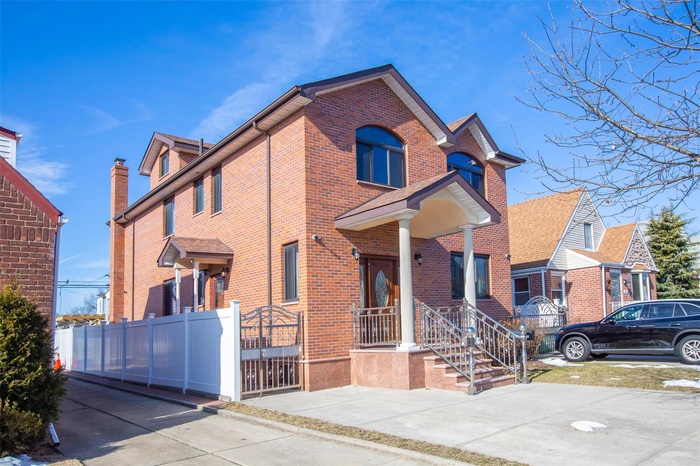 Traditional-style house with brick siding, a chimney, and fence