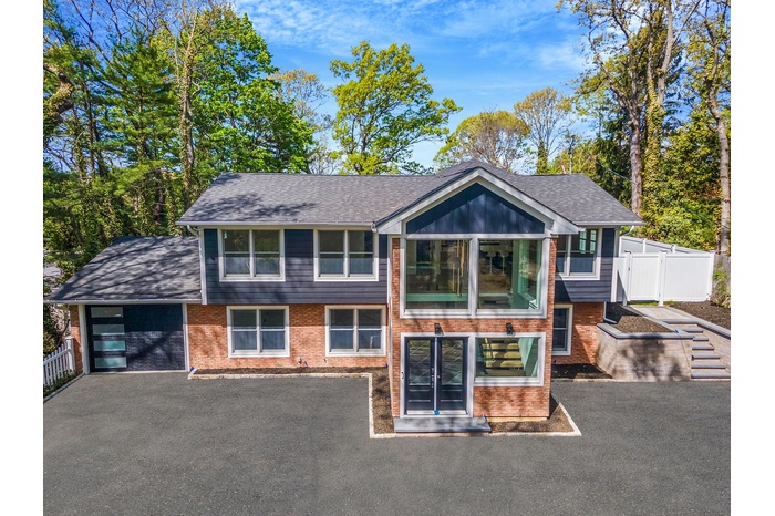 View of front facade featuring an attached garage, asphalt driveway, brick siding, and a shingled roof