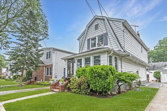 Dutch colonial featuring a gambrel roof, a front lawn, and a chimney