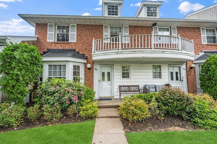 View of front of house featuring a balcony, covered porch, and brick siding