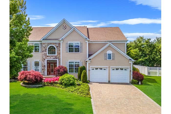 View of front of house featuring decorative driveway, stone siding, a garage, and a shingled roof