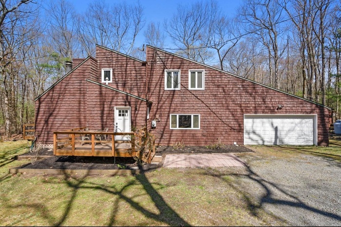 Rear view of house with a wooden deck, a yard, and driveway