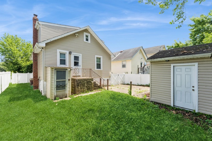 Rear view of house featuring a fenced backyard and a chimney