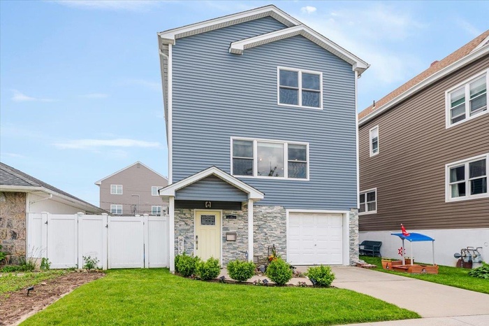 View of front of house featuring a garage, concrete driveway, stone siding, and a gate
