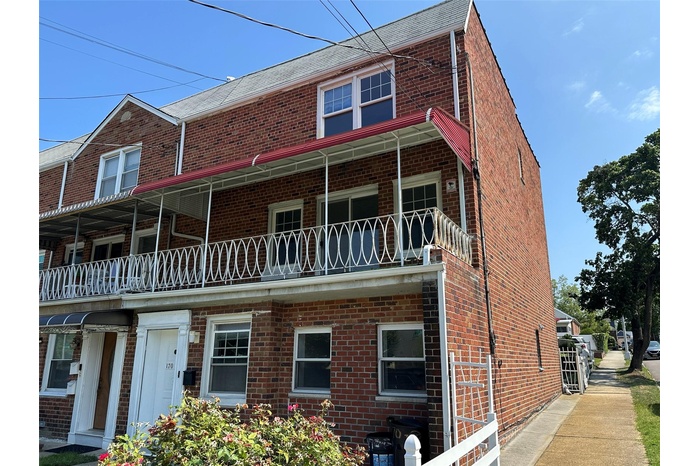View of front of home featuring brick siding and a balcony