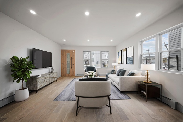 Living room with light wood finished floors, a wealth of natural light, and baseboard heating