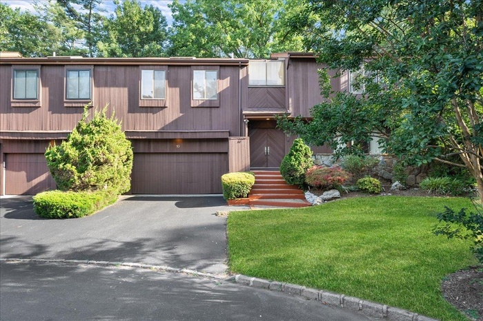 View of front facade with a garage, a front lawn, and driveway