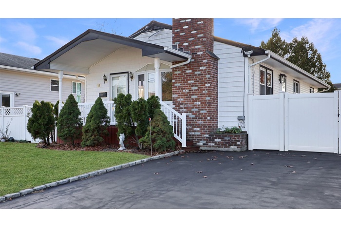 View of front of house with a chimney, brick siding, and a gate