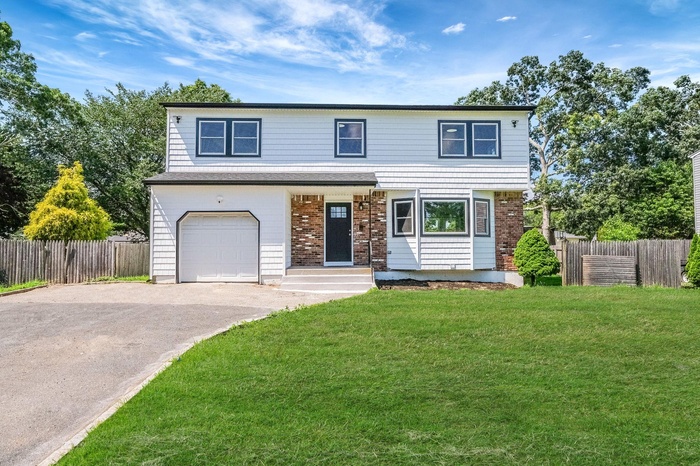 View of front facade featuring an attached garage, driveway, and brick siding