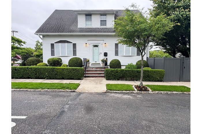 View of front of house with a shingled roof and a gate
