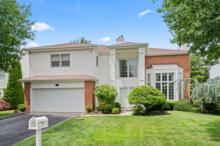 View of front of home featuring a garage, driveway, a chimney, a front yard, and brick siding