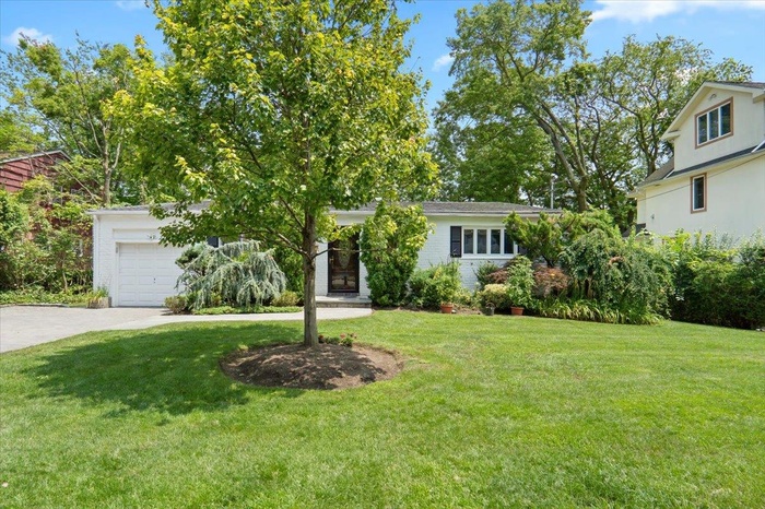 View of front of property with a garage, concrete driveway, and a front yard
