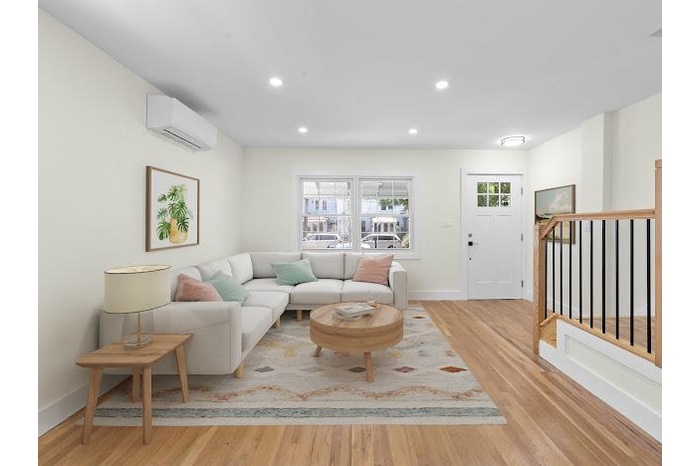 Living area with a wall mounted air conditioner, plenty of natural light, light wood-style floors, and recessed lighting