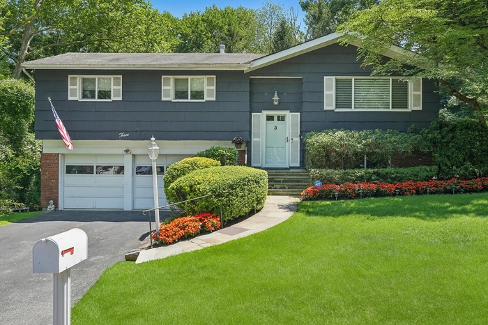 Split foyer home with asphalt driveway, a front yard, an attached garage, and brick siding