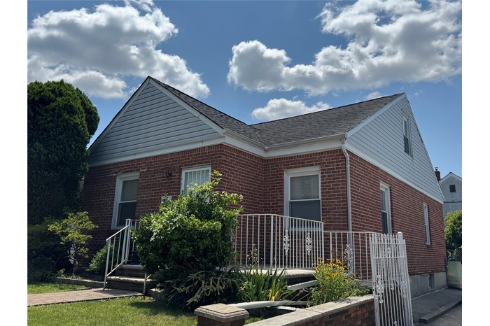 View of front of home featuring brick siding and roof with shingles