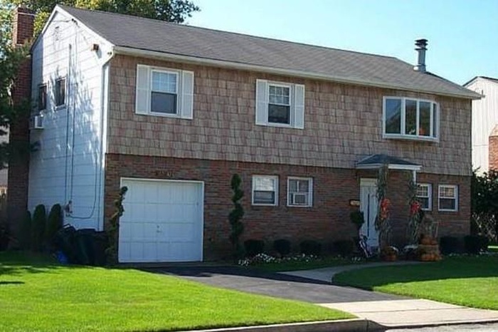 View of front of house with a garage, a front lawn, a chimney, and brick siding