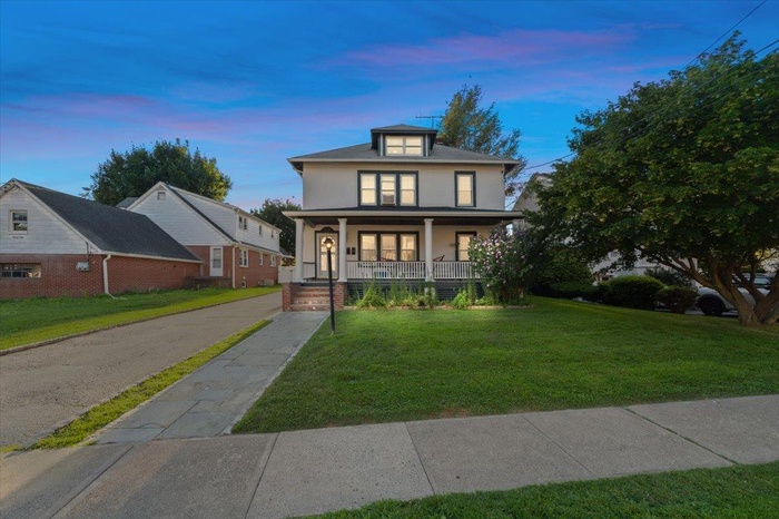 Traditional style home with covered porch, a front lawn, and stucco siding