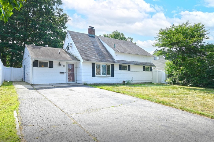 View of front of property with a chimney, driveway, and a shingled roof