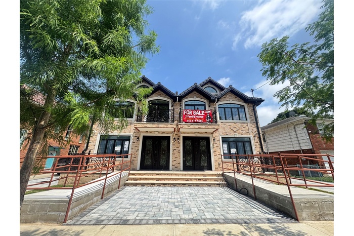 View of front facade featuring french doors, brick siding, and a balcony