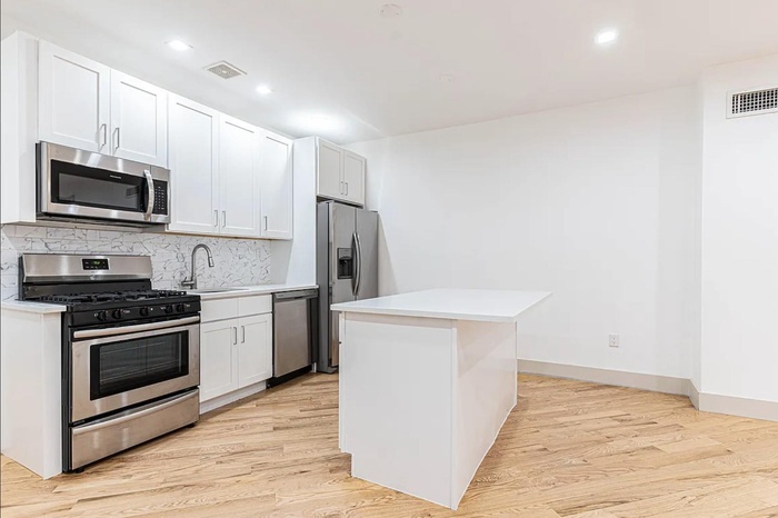 Kitchen with visible vents, backsplash, appliances with stainless steel finishes, light wood-style floors, and a sink
