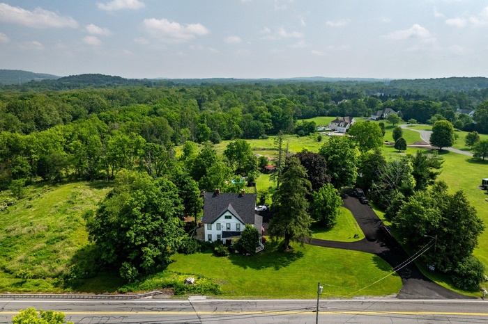 Aerial view of property and surrounding area with a forest