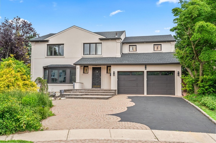 View of front of property with asphalt and paver driveway, stucco siding, an attached garage, and a brand new 40yr shingled roof
