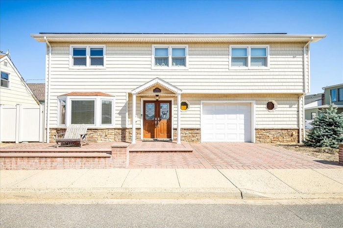 View of front of property with stone siding, decorative driveway, and an attached garage