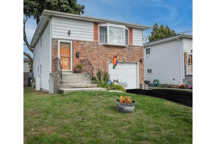Split level home with a garage, driveway, brick siding, and a front yard