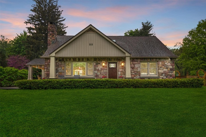 View of front facade featuring stone siding, roof with shingles, and a front yard