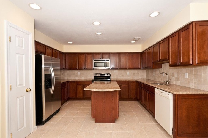 Kitchen featuring stainless steel appliances, a center island, backsplash, recessed lighting, and light tile patterned floors