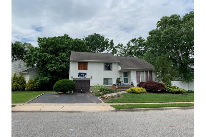 Split level home featuring a front yard, aphalt driveway, and an attached garage