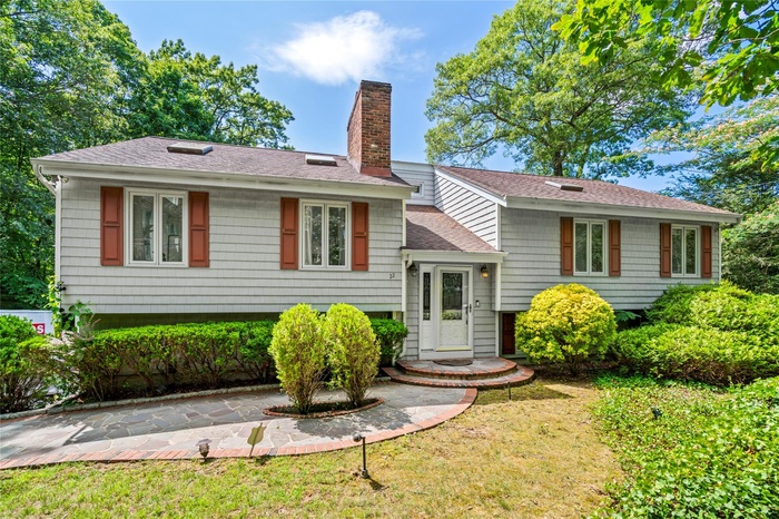 View of front of property with roof with shingles, a chimney, and a front yard